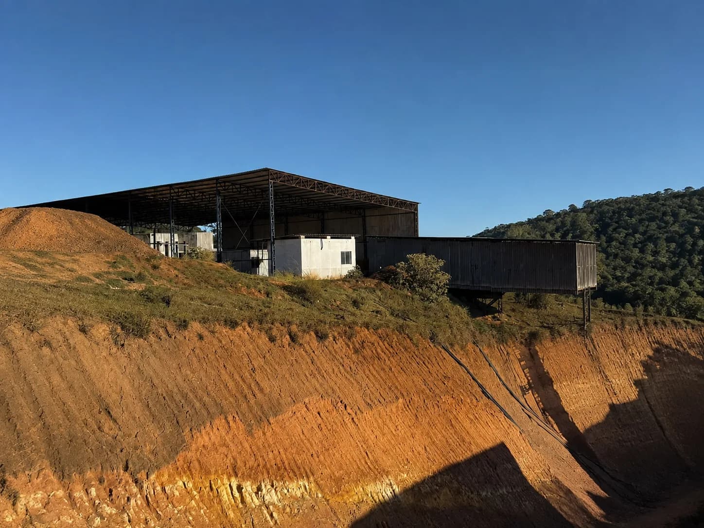 Galpão da planta na borda da cava, com o talude à frente