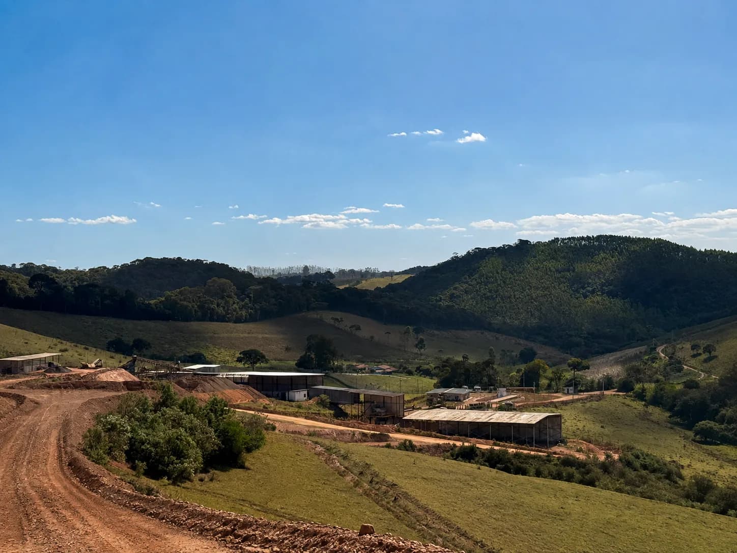 Vale com vegetação no entorno da Mina Carijós, com a planta e a estrada de acesso ao fundo